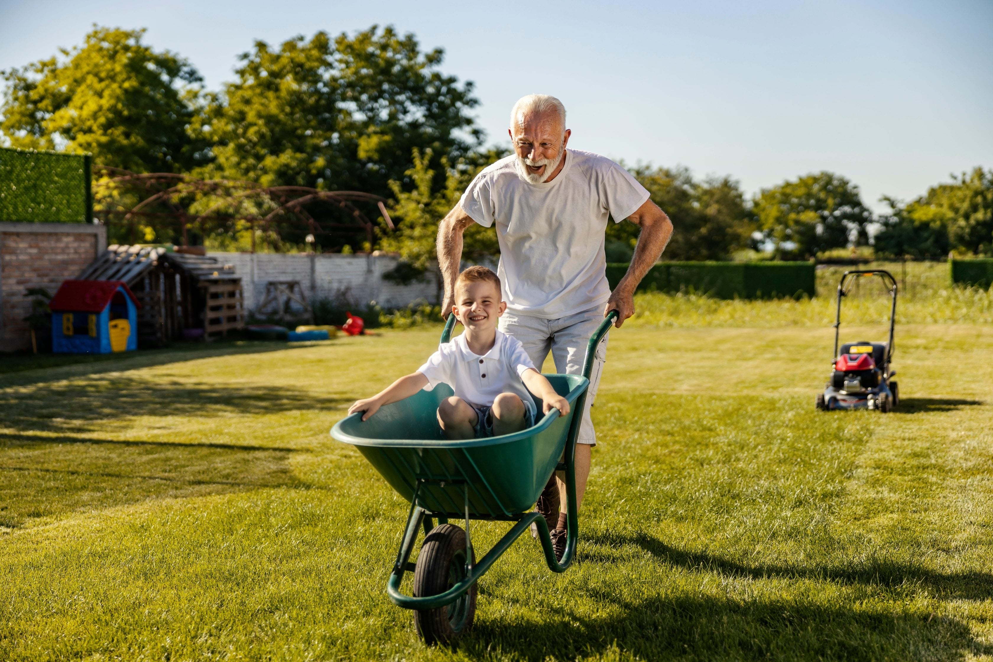 Avô brincando com seu neto usando um carrinho de mão