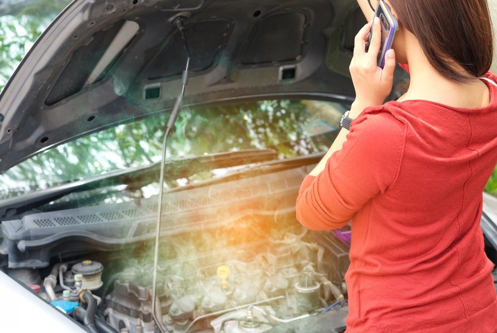 Mulher acionando o seguro após o motor do carro superaquecer
