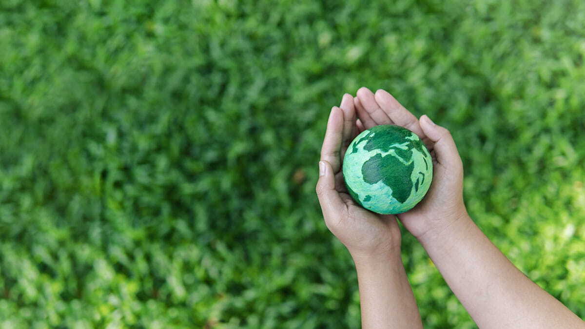 Pessoa segurando um globo de terra verde simbolizando sustentabilidade