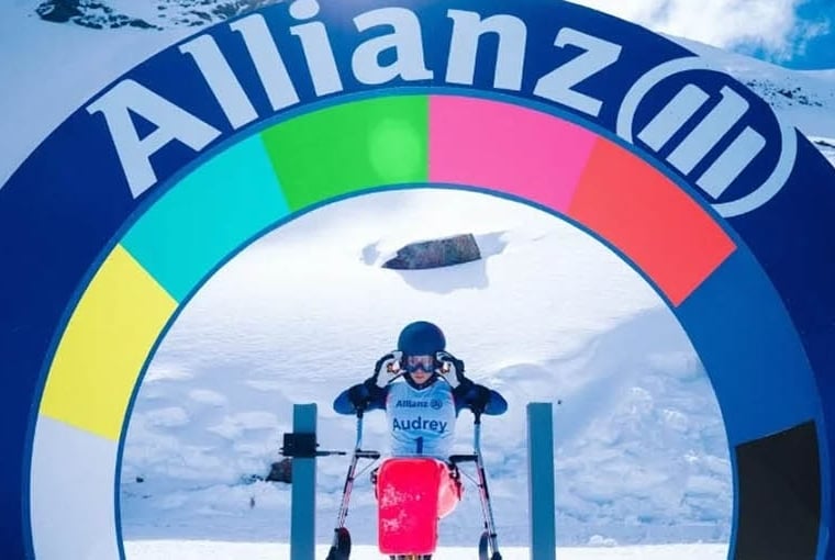 Atleta olímpico esquiando em montanha com neve e totem com o logo da Allianz ao fundo