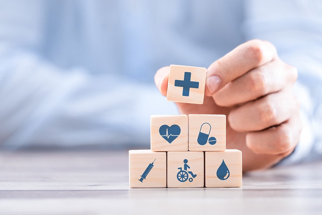 Homem segurando cubos de madeira com ícones de cuidados médicos