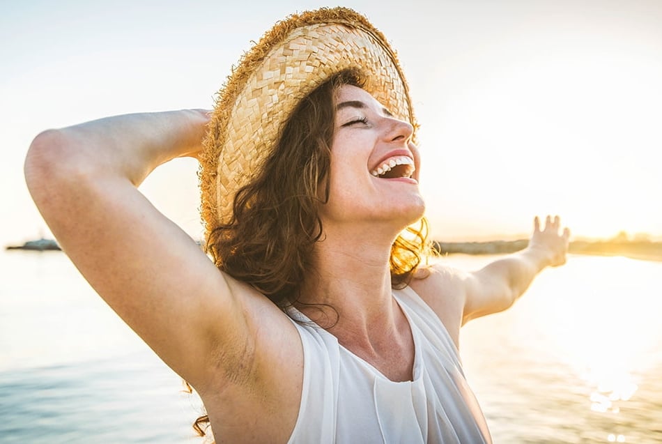 Mulher sorrindo em pôr do sol na praia