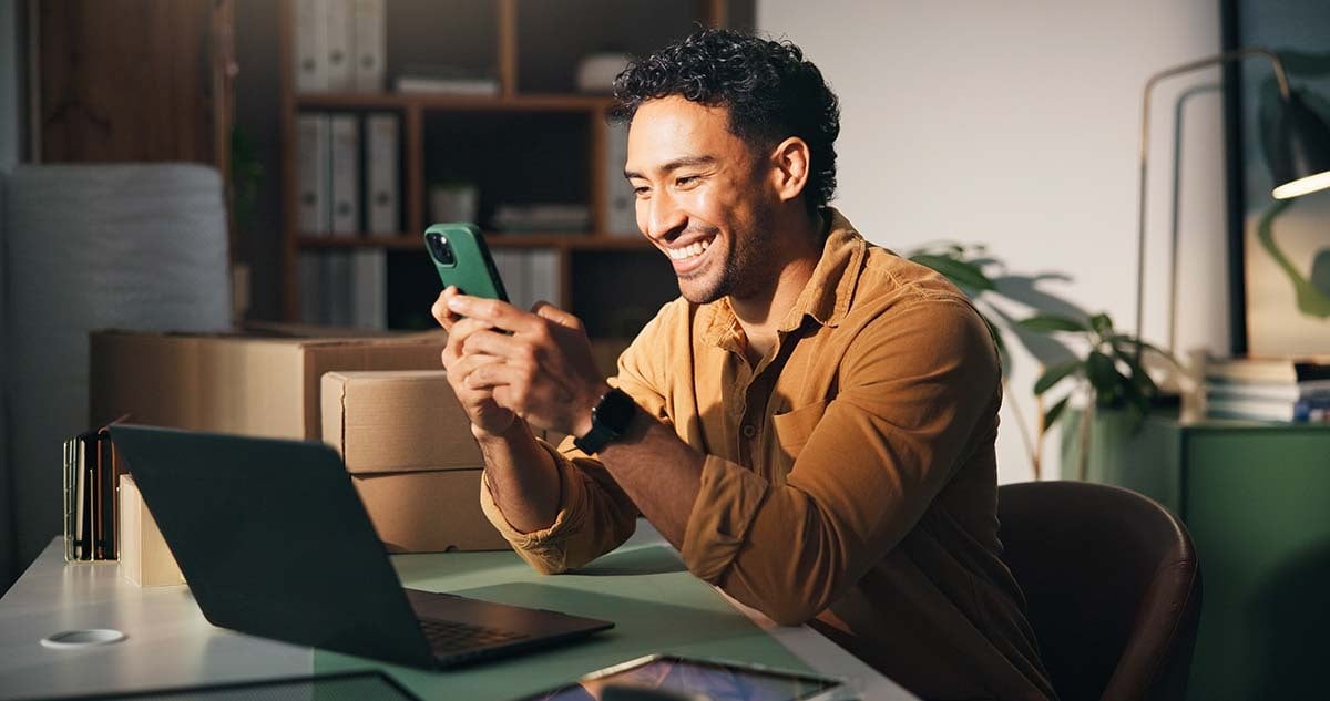 Homem sorrindo e usando o celular