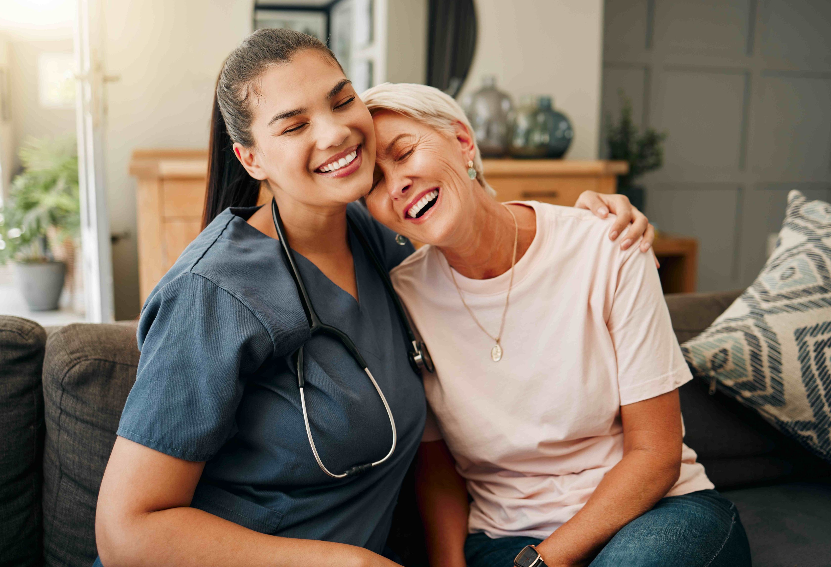 Duas mulheres sorrindo juntas no sofá, demonstrando carinho e cumplicidade