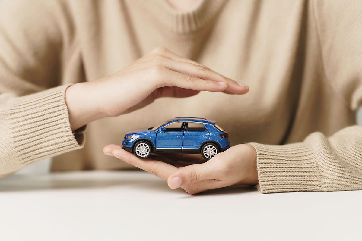 Mulher segurando miniatura de carro com as mãos 