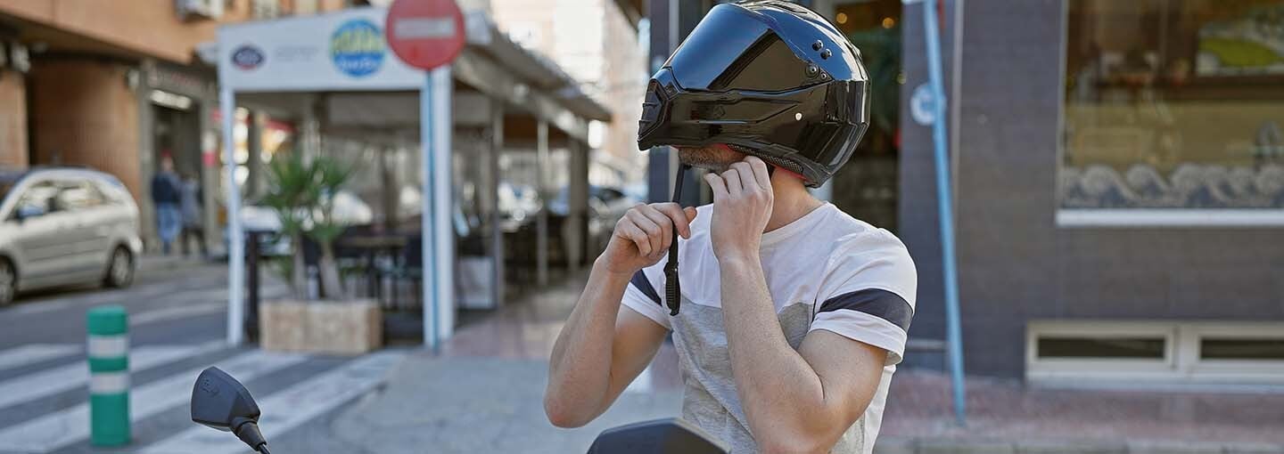 Homem colocando capacete em cima de sua moto