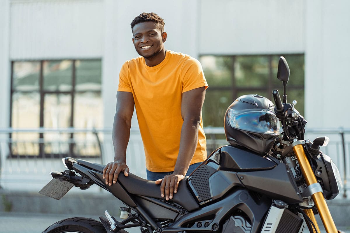 Homem sorrindo em frente de sua moto