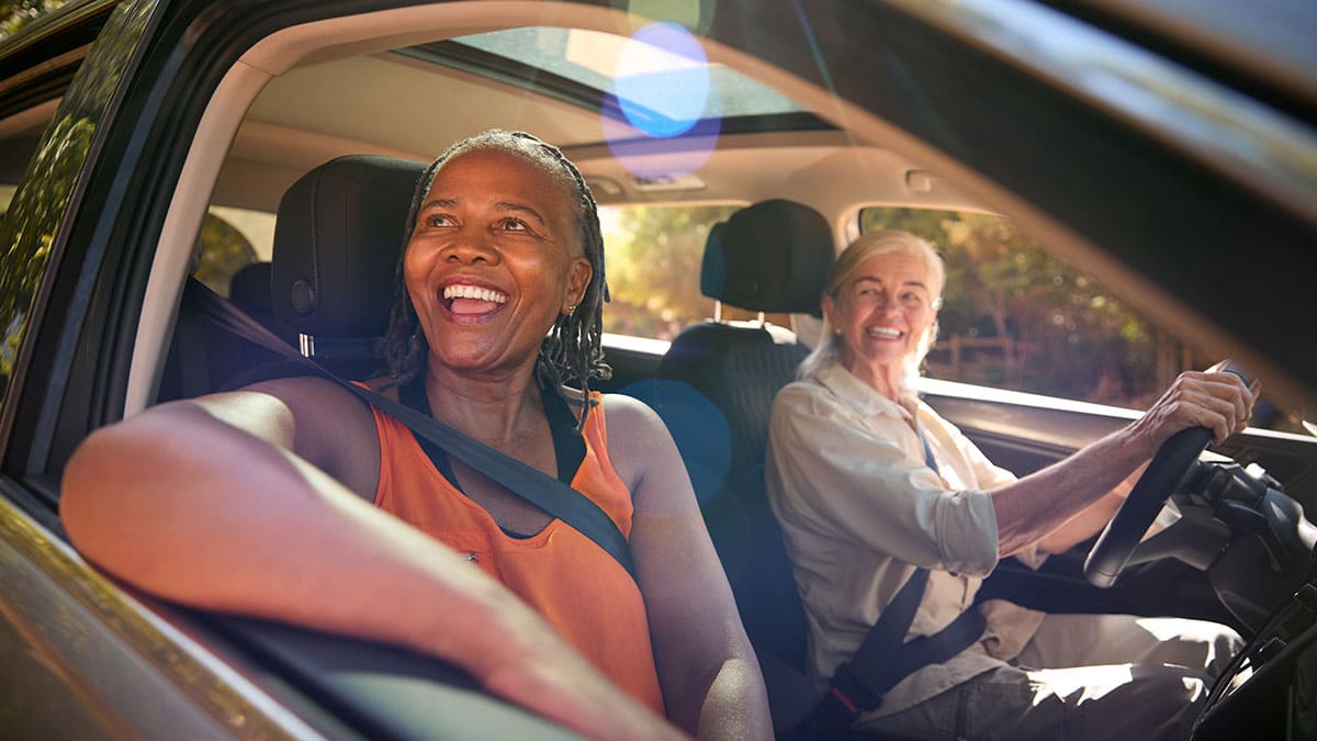 Duas senhoras sorrindo e viajando de carro 