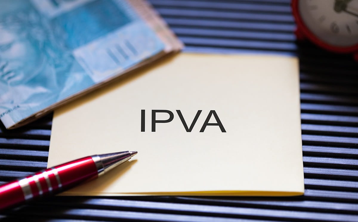 Bloco de notas com a sigla IPVA, notas de dinheiro e caneta