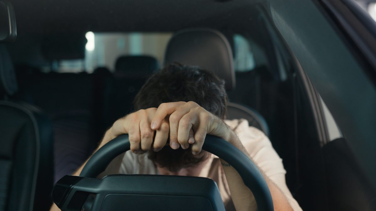 Motorista preocupado e de cabeça baixa ao volante