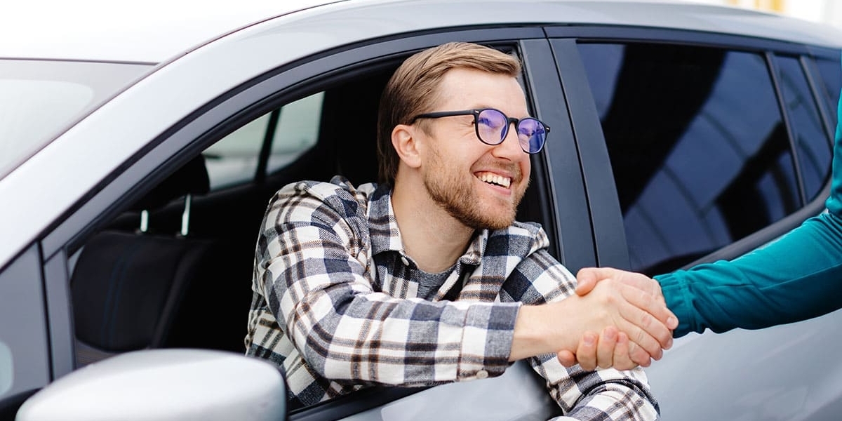 Homem apertando as mãos do vendedor após comprar um carro