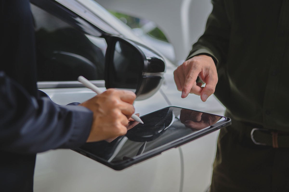 Vendedor anotando informações do cliente em tablet durante cotação de seguro auto