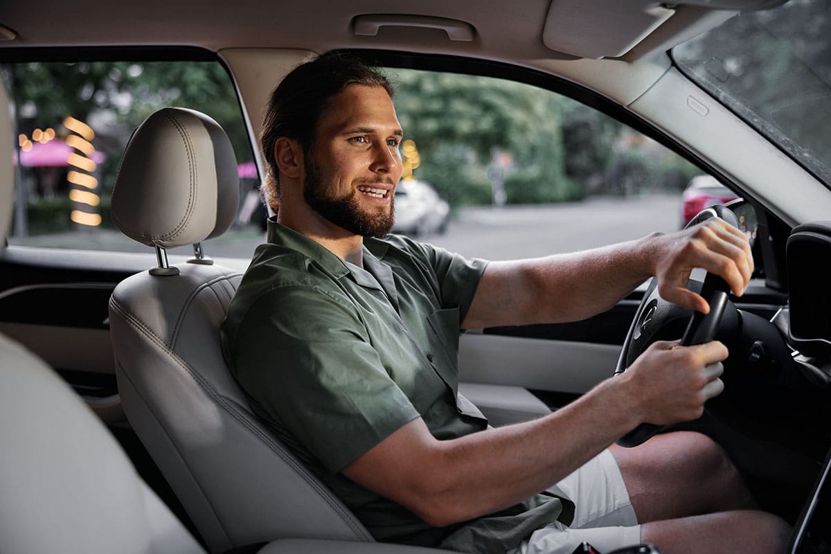 Homem sorrindo enquanto dirige carro