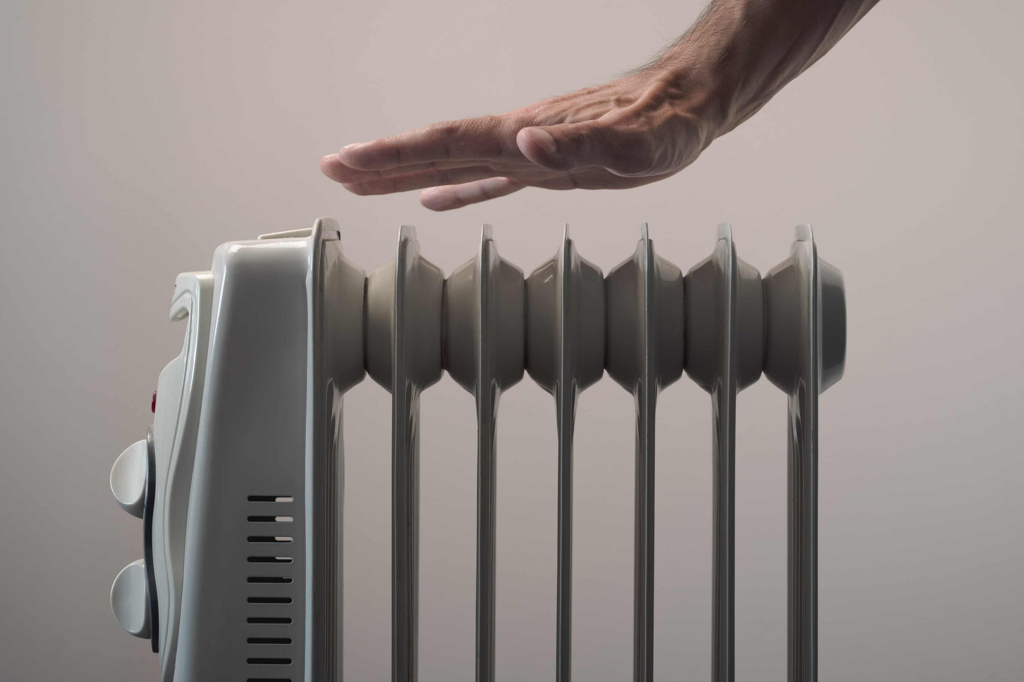 Homem com a mão próximo a um aquecedor elétrico