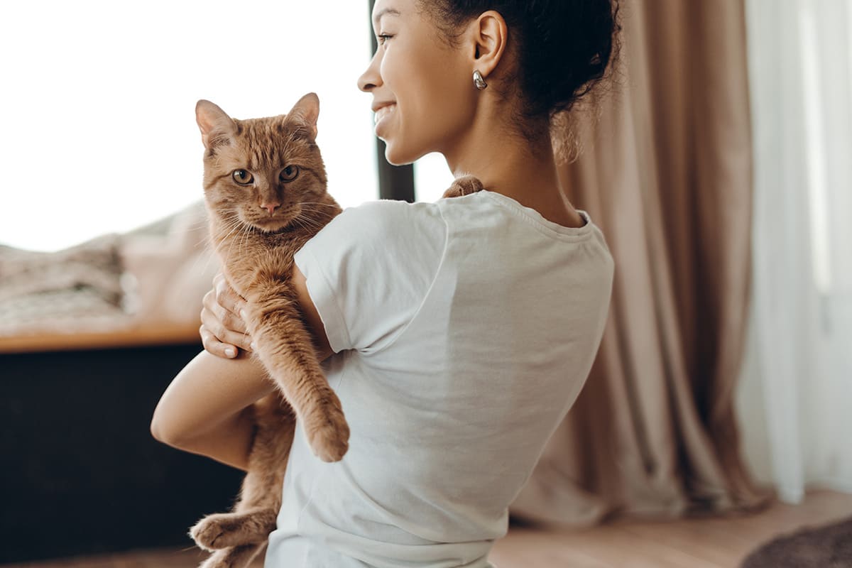 Mulher sorrindo em casa com seu gato no colo