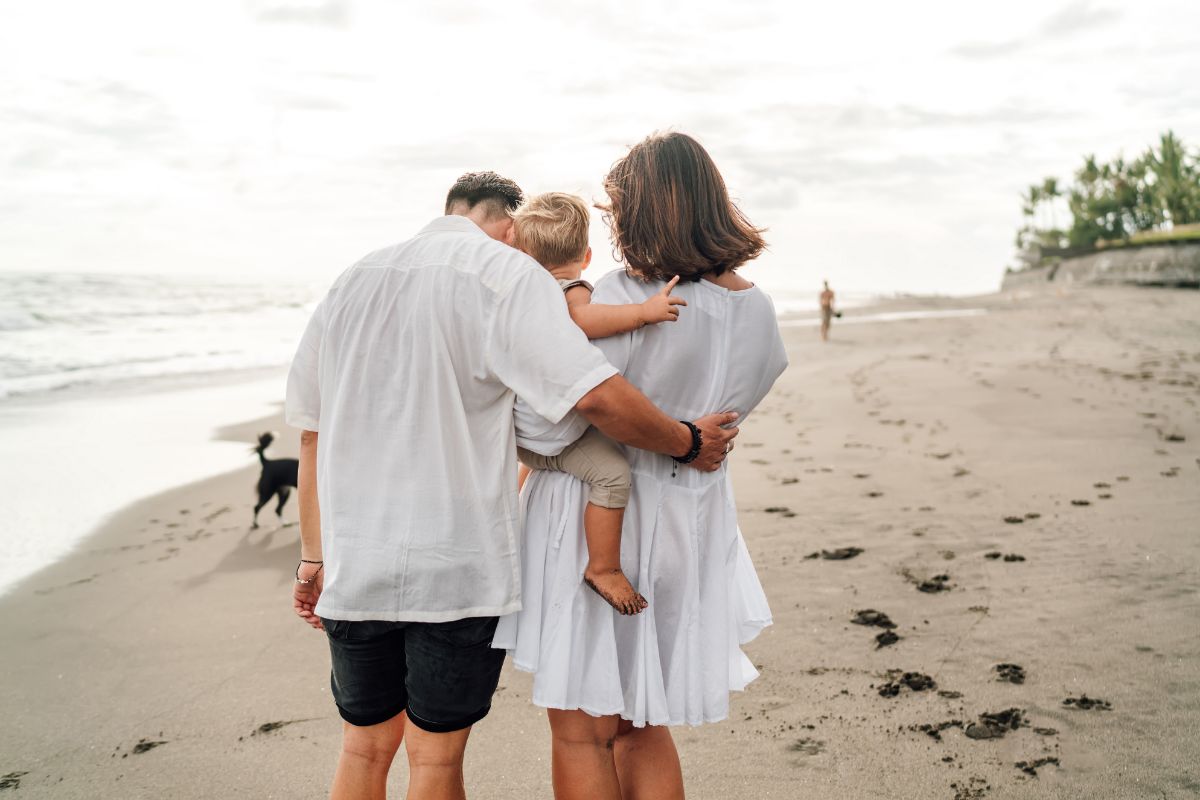 Família caminhando na areia da praia