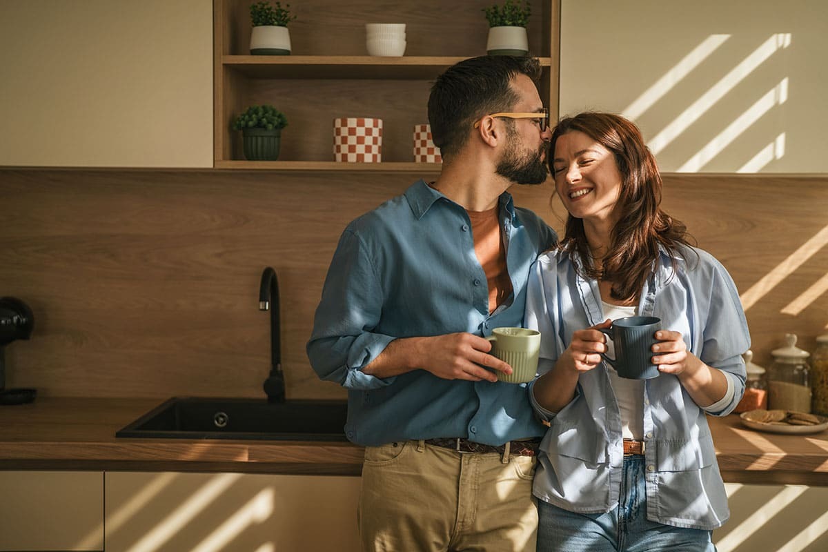 Casal tomando café e se abraçando na cozinha