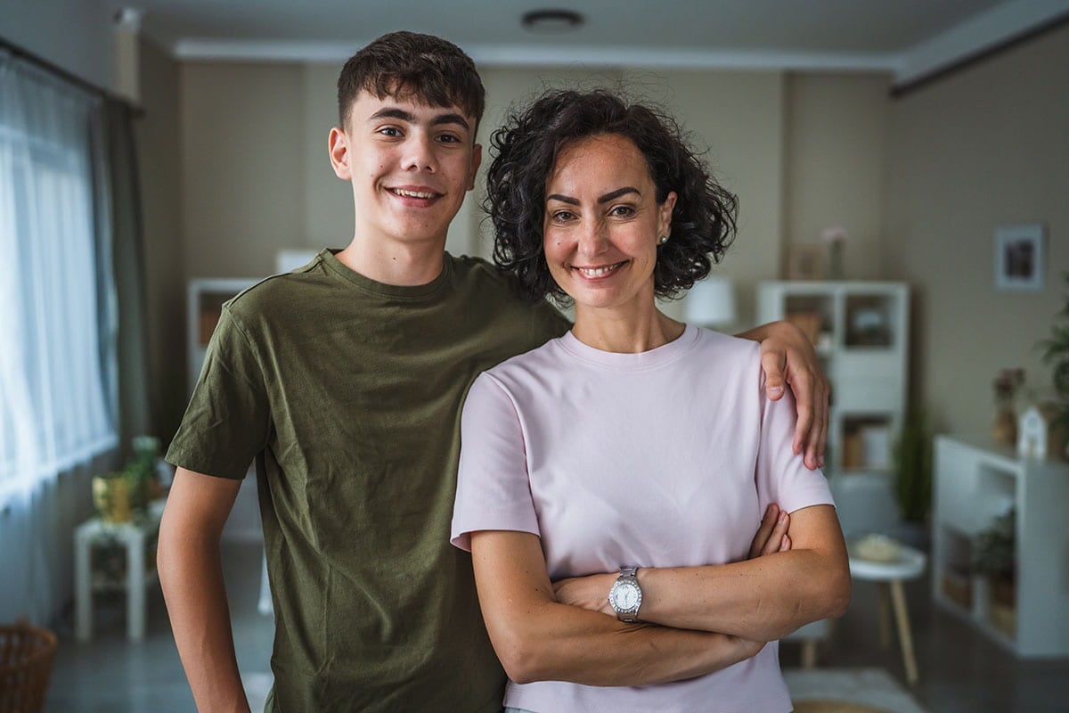 Mãe e filho abraçados em casa e sorrindo