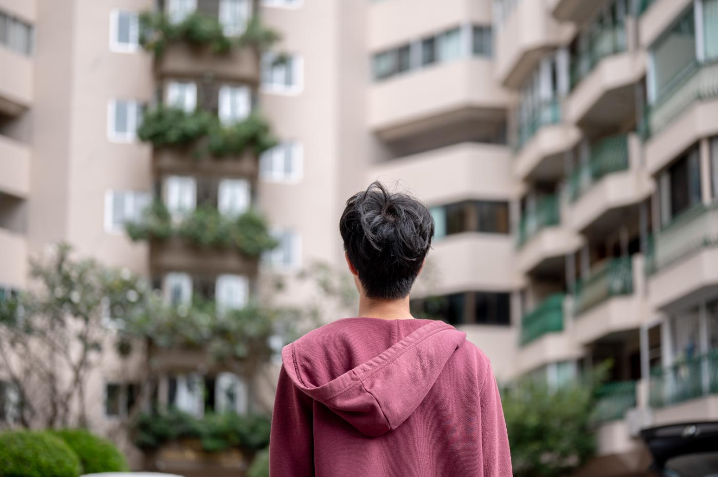 Homem visto de costas na área comum de um condomínio