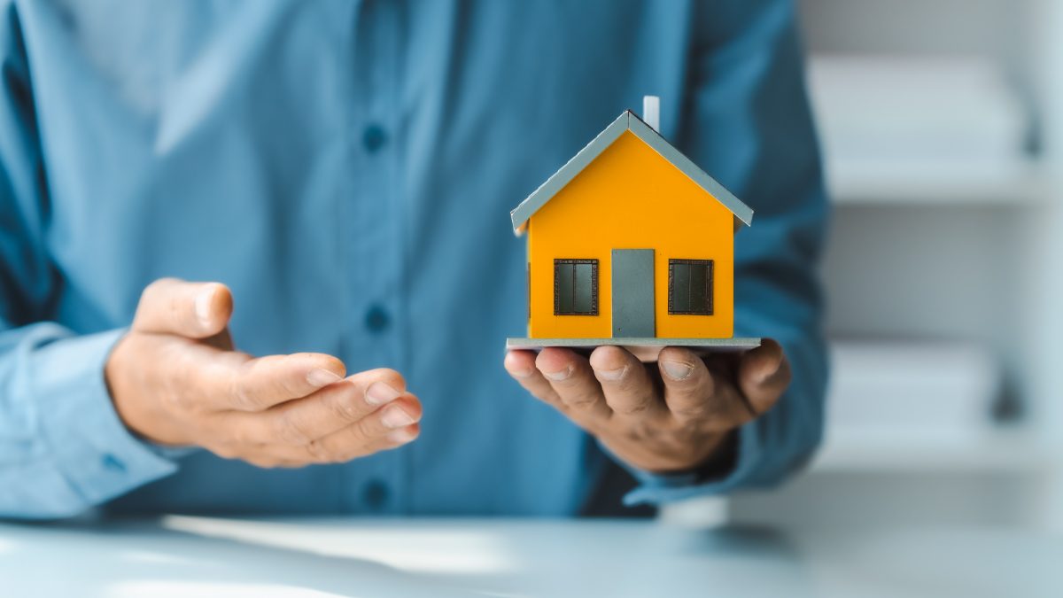 Homem com miniatura de casa na mão representando o seguro residencial