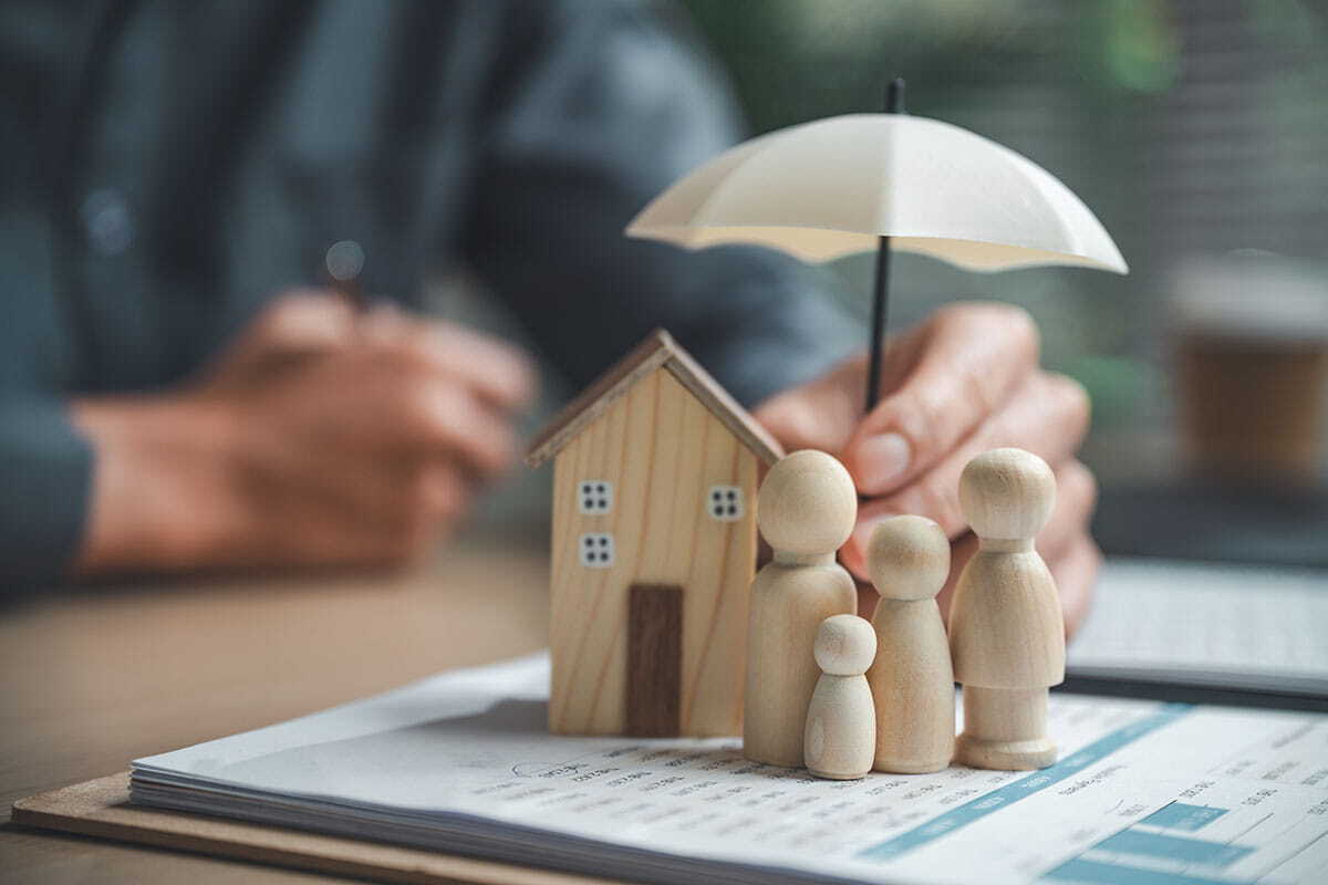 Bonecos de família com casa protegidos por guarda-chuva, conceito de seguro residencial 