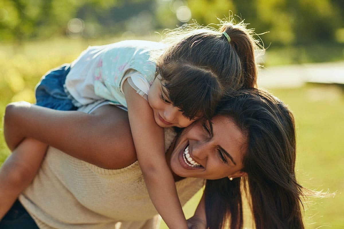 Mãe e filha sorrindo e brincando juntas