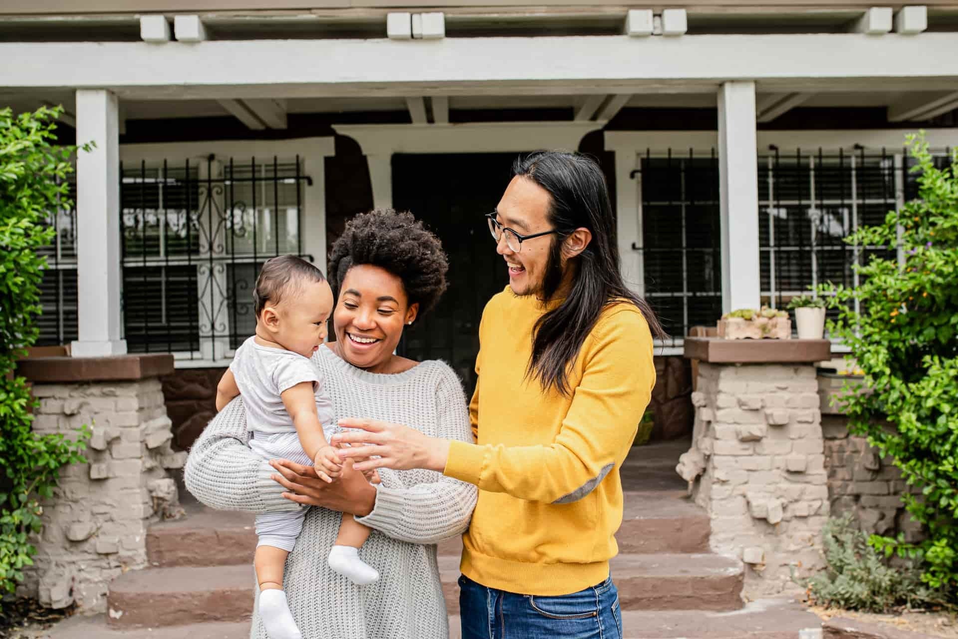 Família feliz em frente a sua residência