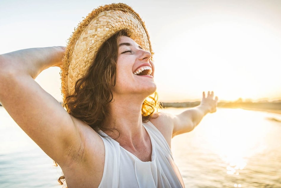 Mulher sorrindo em pôr do sol na praia