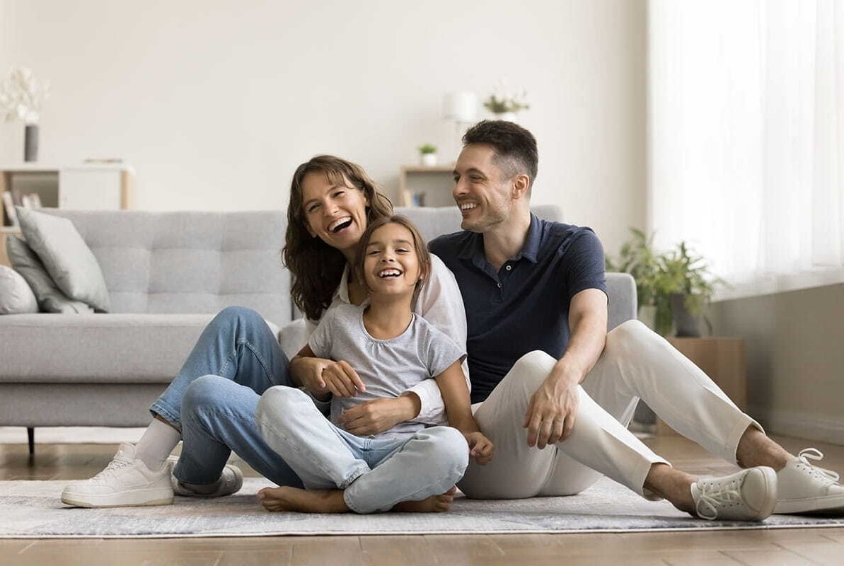 Família feliz sorrindo sentados no chão da sala