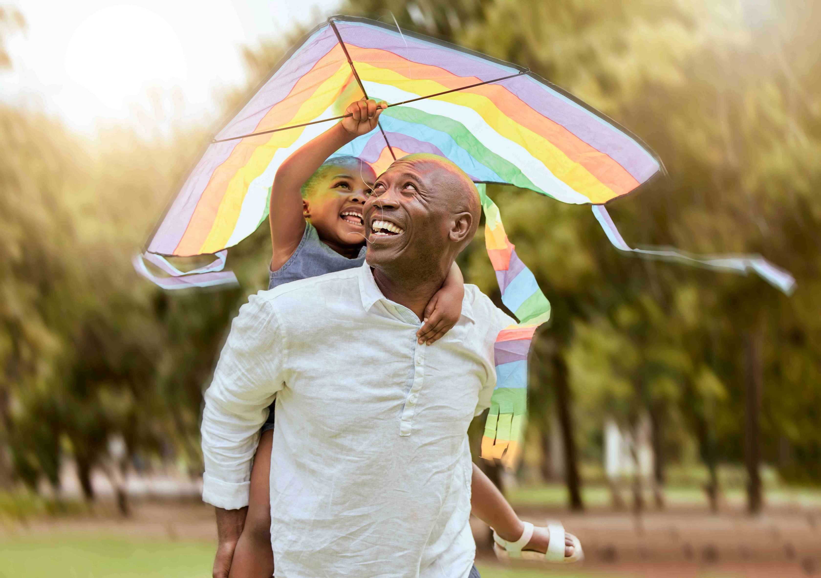 Pai e filho sorrindo e brincando com pipa em um parque