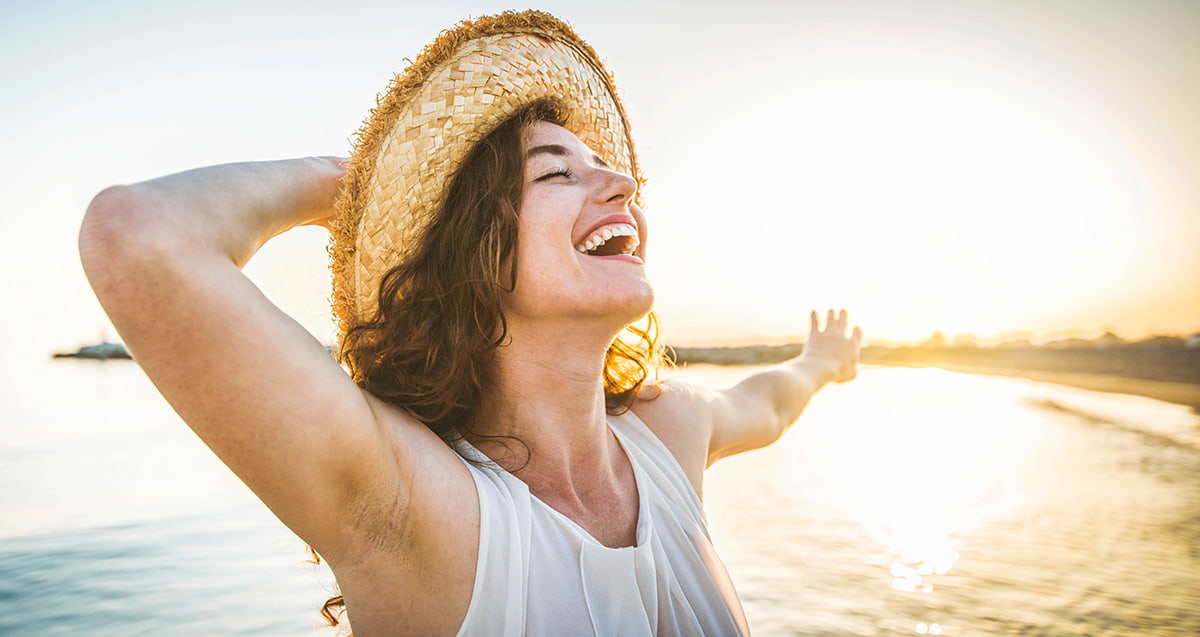 Mulher sorrindo em pôr do sol na praia