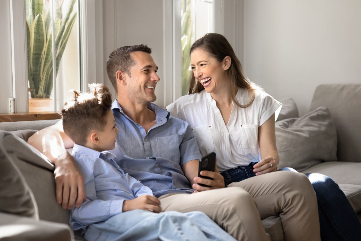 Família feliz sentada no sofá de casa