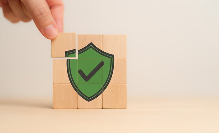 Pessoa montando quebra cabeça de madeira com símbolo de proteção verde ao meio