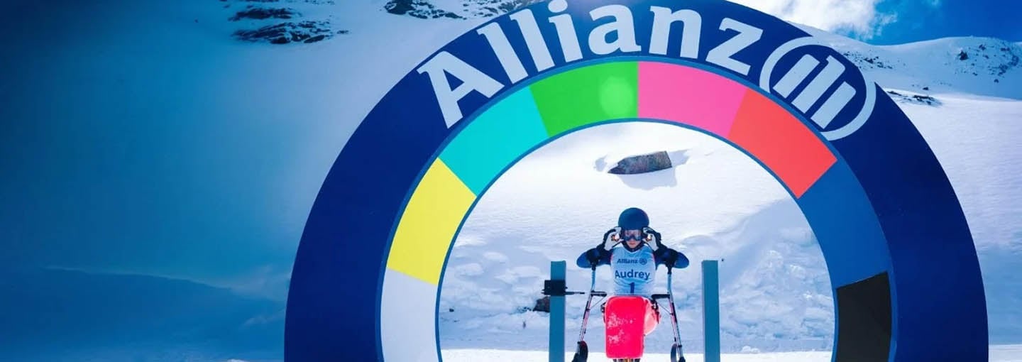 Atleta olímpico esquiando em montanha de neve e totem com o logo da Allianz ao fundo