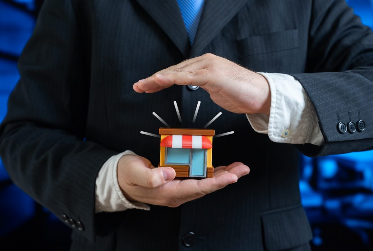 Homem segurando um ícone de pequeno negócio representando o seguro empresarial PME