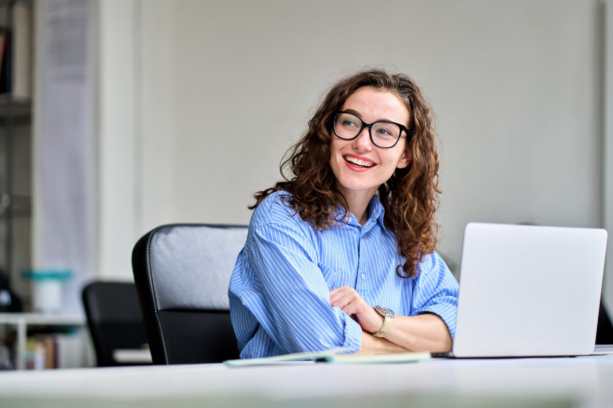 Mulher sorrindo no trabalho em frente ao  seu computador