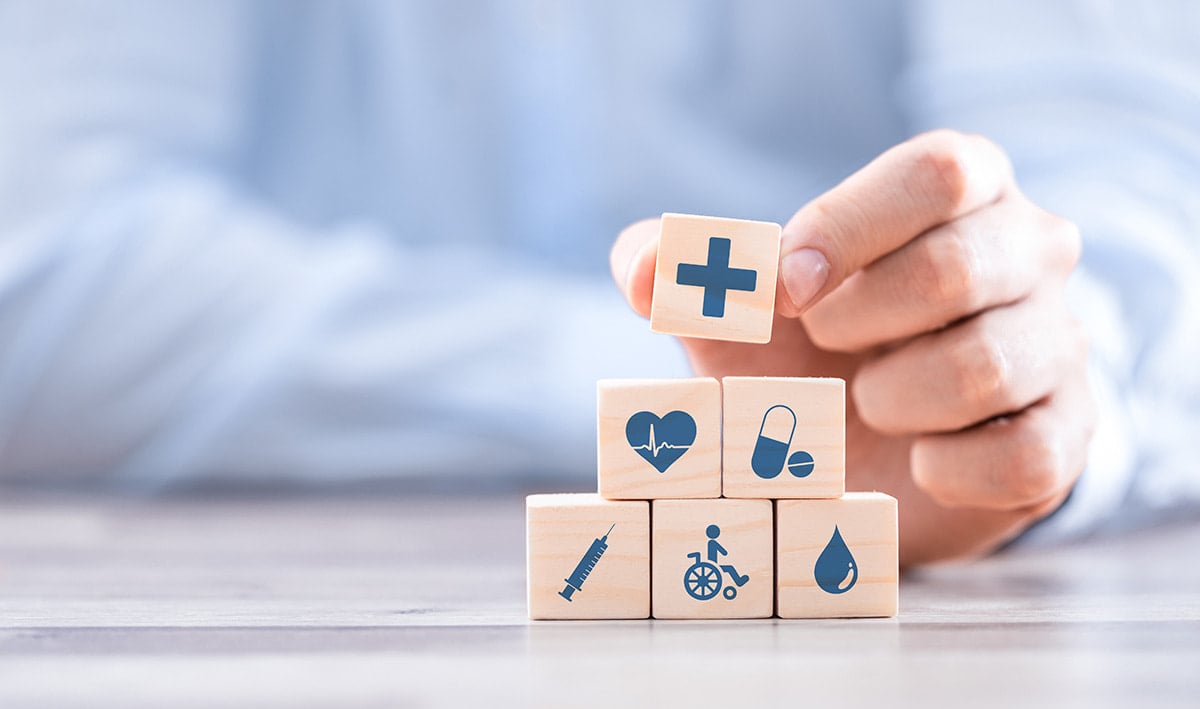 Homem segurando cubos de madeira com ícones de cuidados médicos