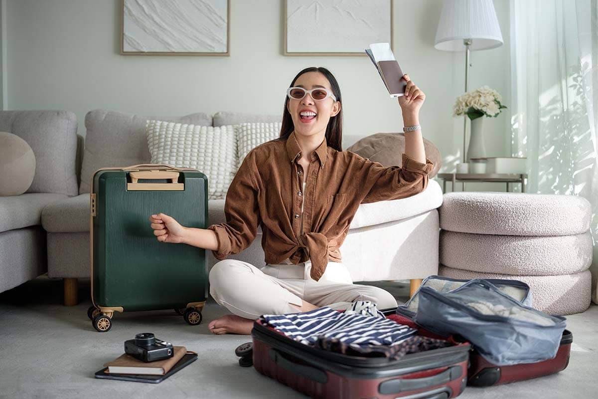 Mulher sorridente arrumando suas malas com o passaporte em mãos