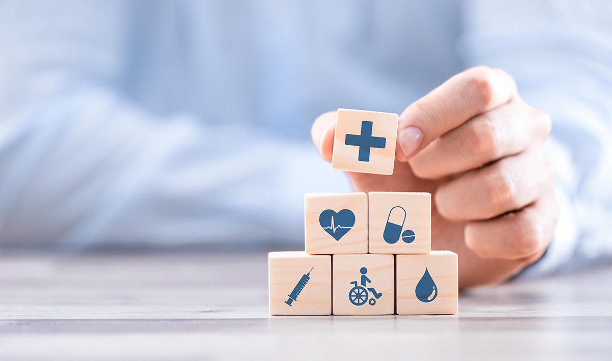 Homem segurando cubos de madeira com ícones de cuidados médicos