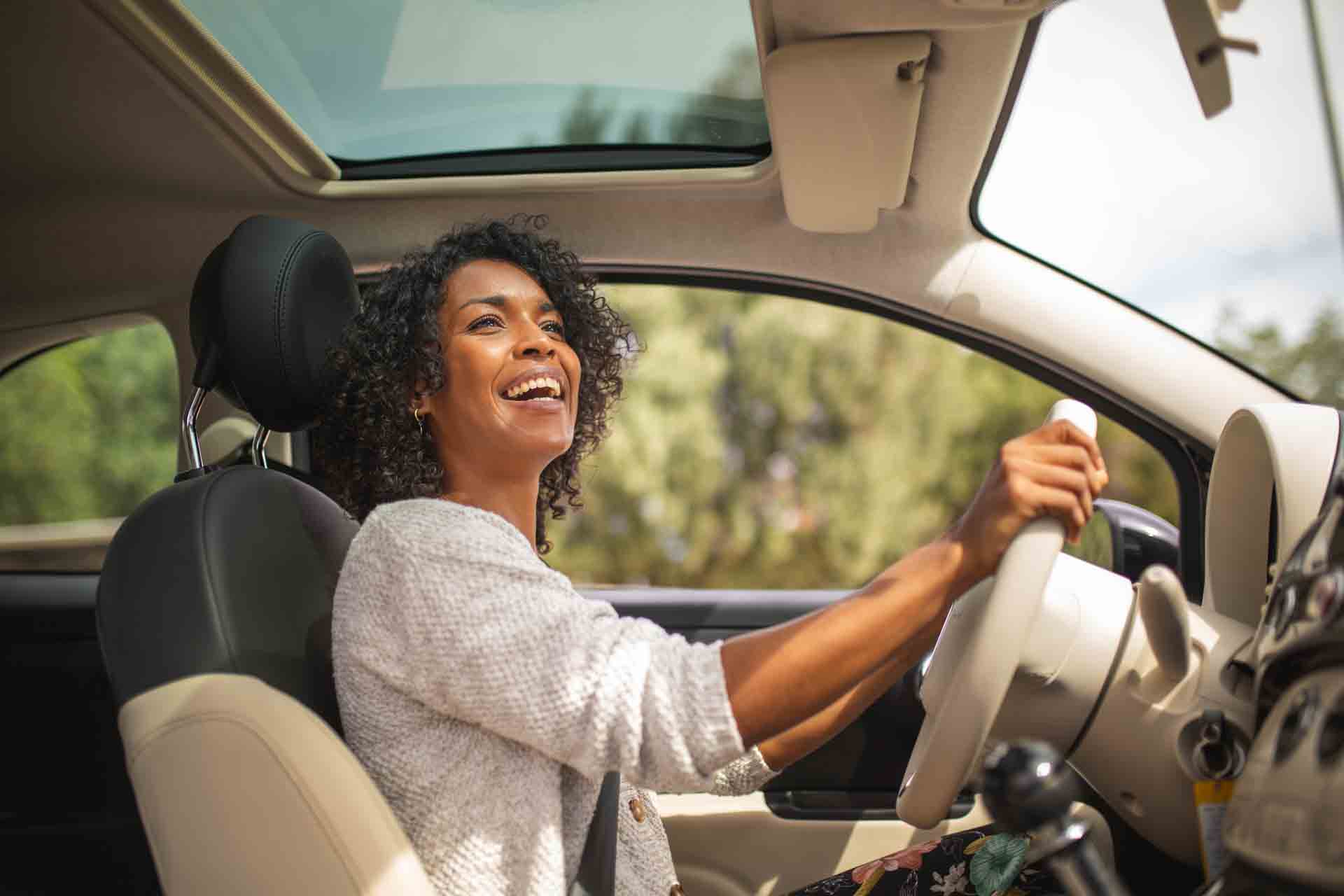 Mulher sorrindo enquanto dirige seu carro