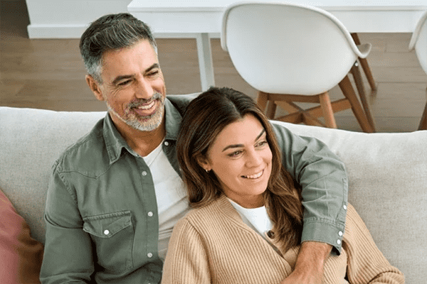 Casal de meia idade sentado no sofá e sorrindo