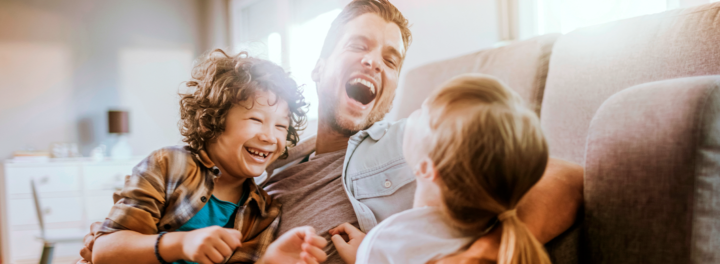 Família feliz com homem segurando criança no colo 