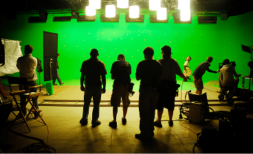 Equipe de gravação em estúdio com tela verde, refletores e câmeras
