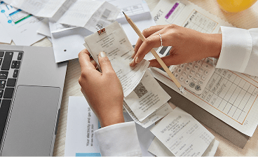 Pessoa analisando notas fiscais e fazendo contas