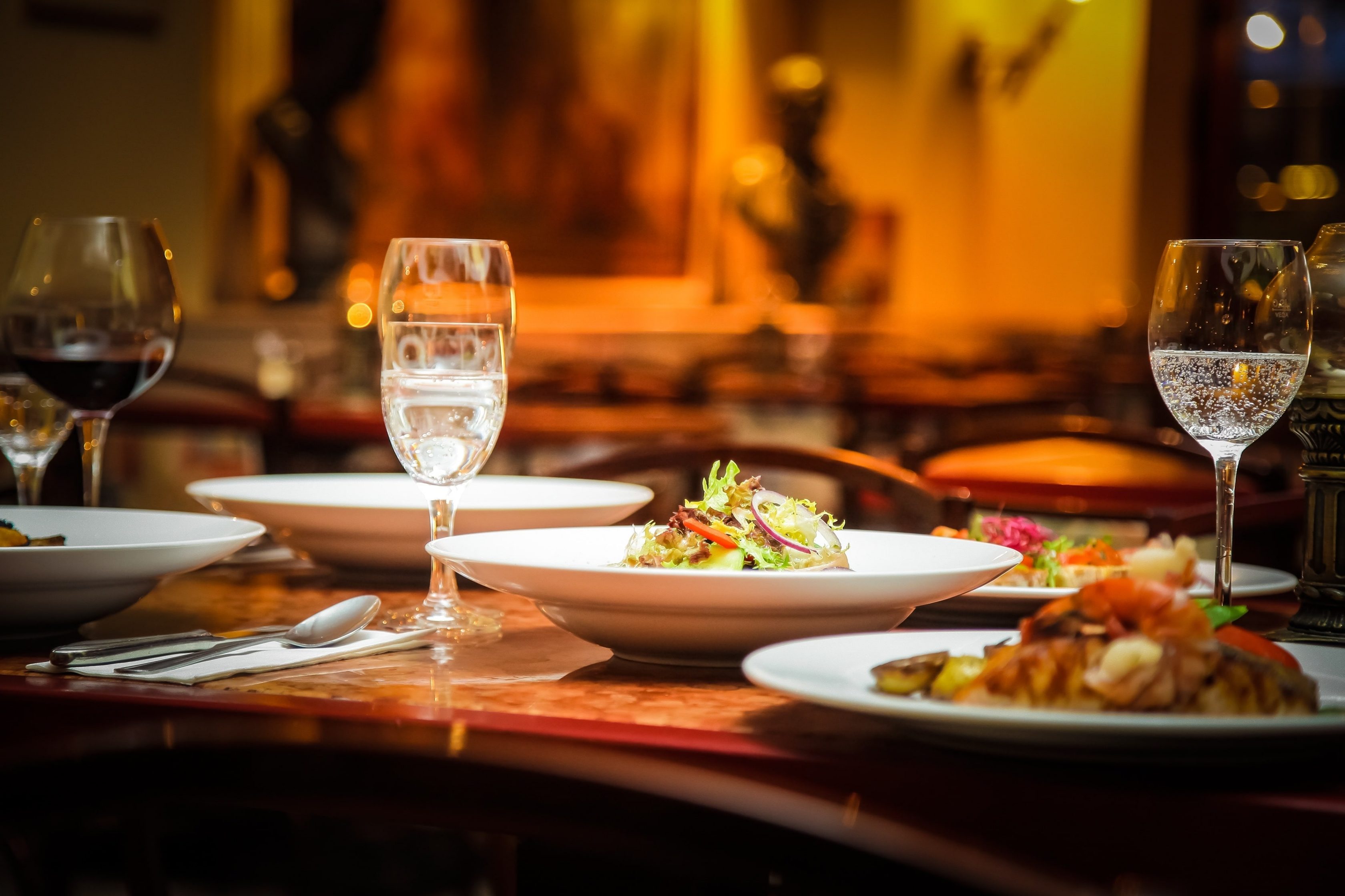 Mesa de restaurante refinado com pratos elaborados e taças cuidadosamente dispostas.