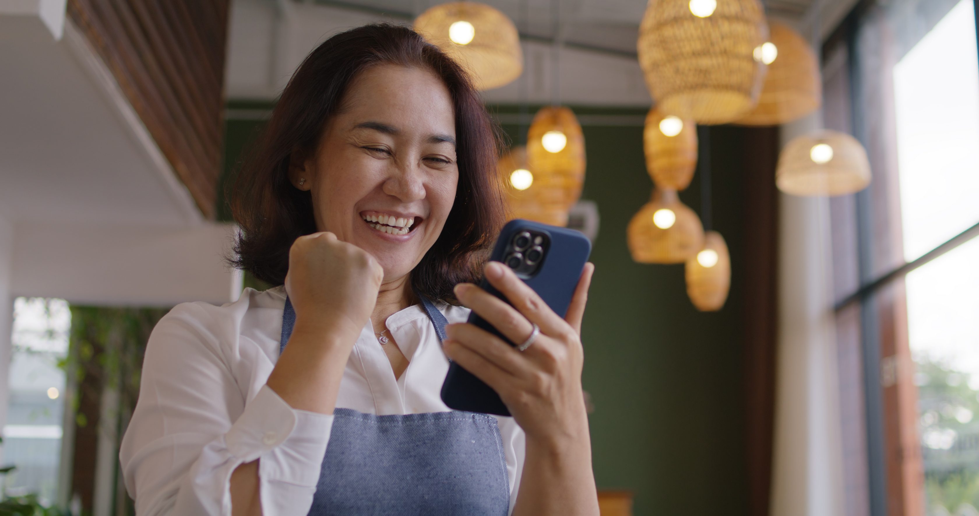 Mulher sorrindo em casa com celular na mão