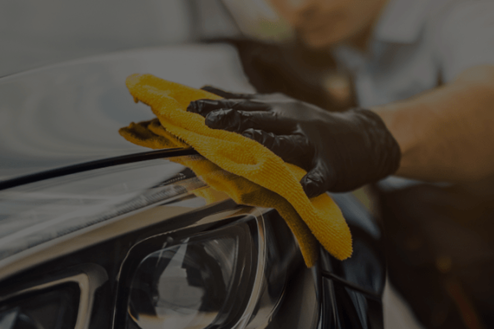 Pessoa limpando a lataria do carro com pano