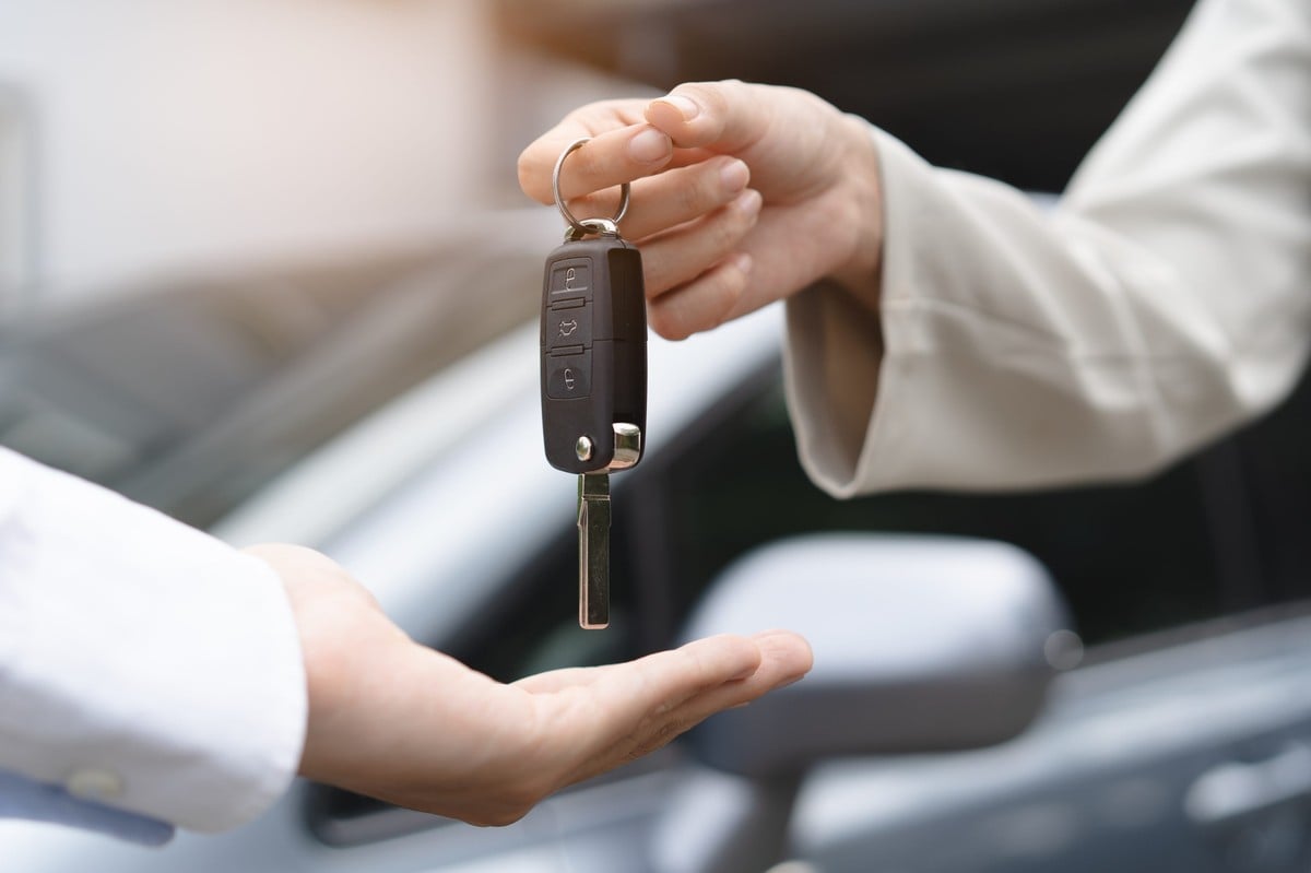 Mulher entregando a chave de um carro para outra
