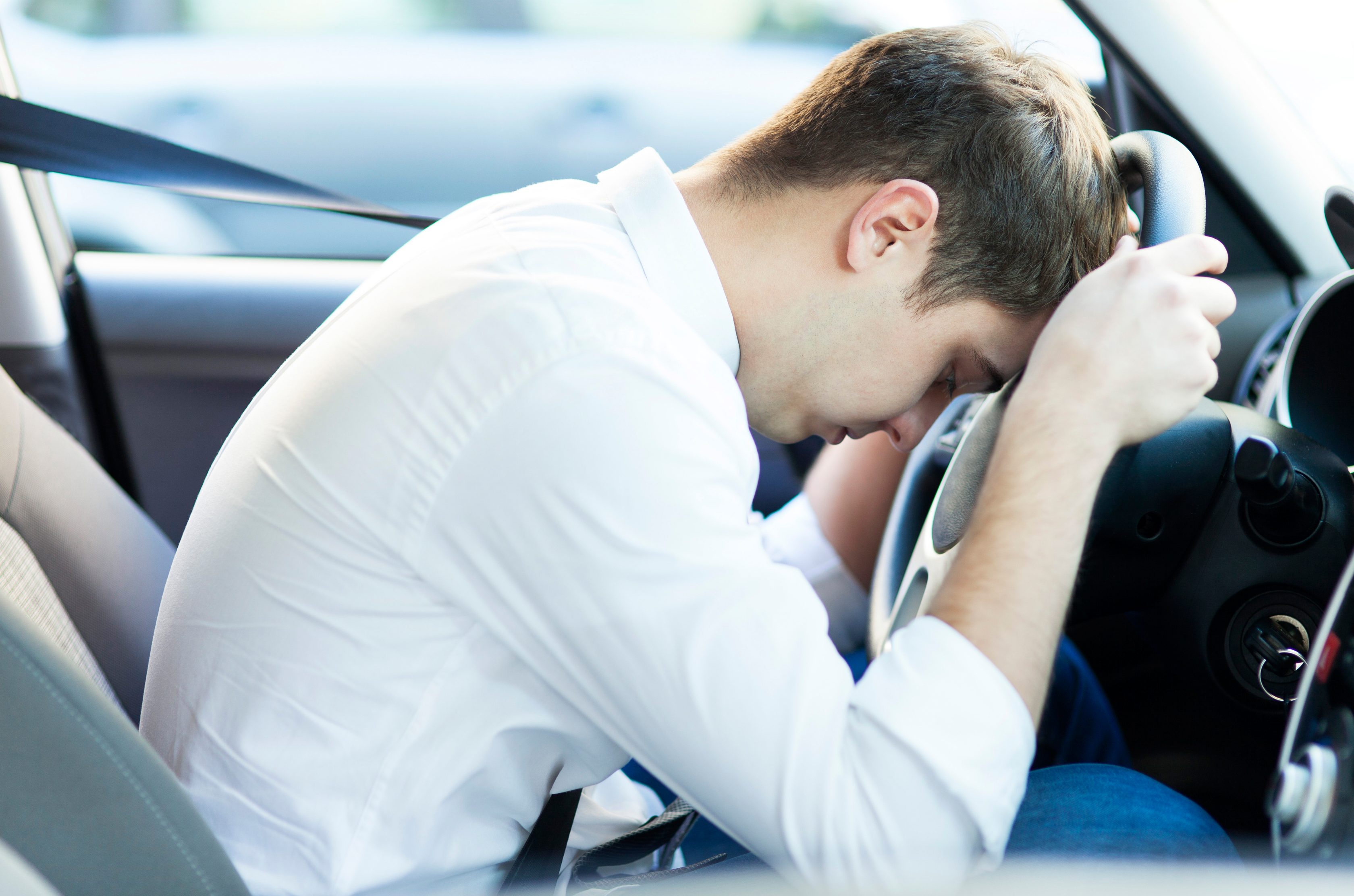 Imagem de um motorista com a cabeça no volante ao lado do texto que fala sobre a frequência ideal para manutenção automotiva
