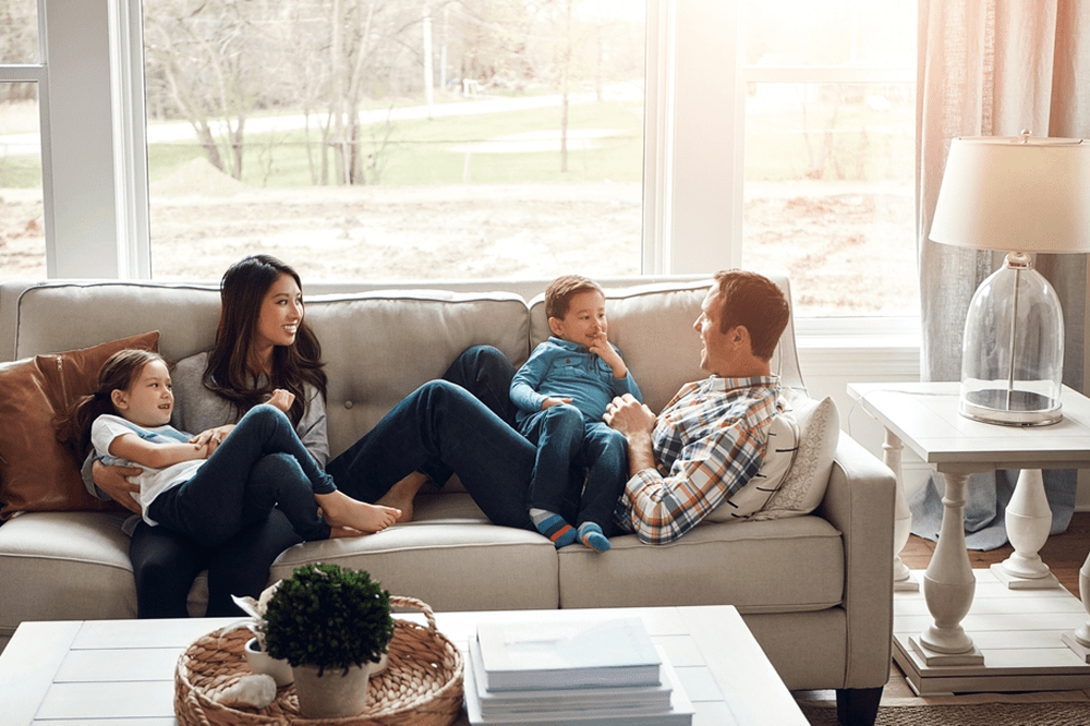 Família conversando no sofá de casa com expressão de conforto e felicidade  